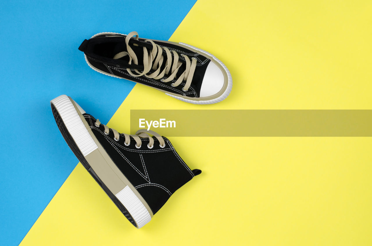 colored background, font, yellow, footwear, studio shot, indoors, no people, shoe, blue, logo, wing