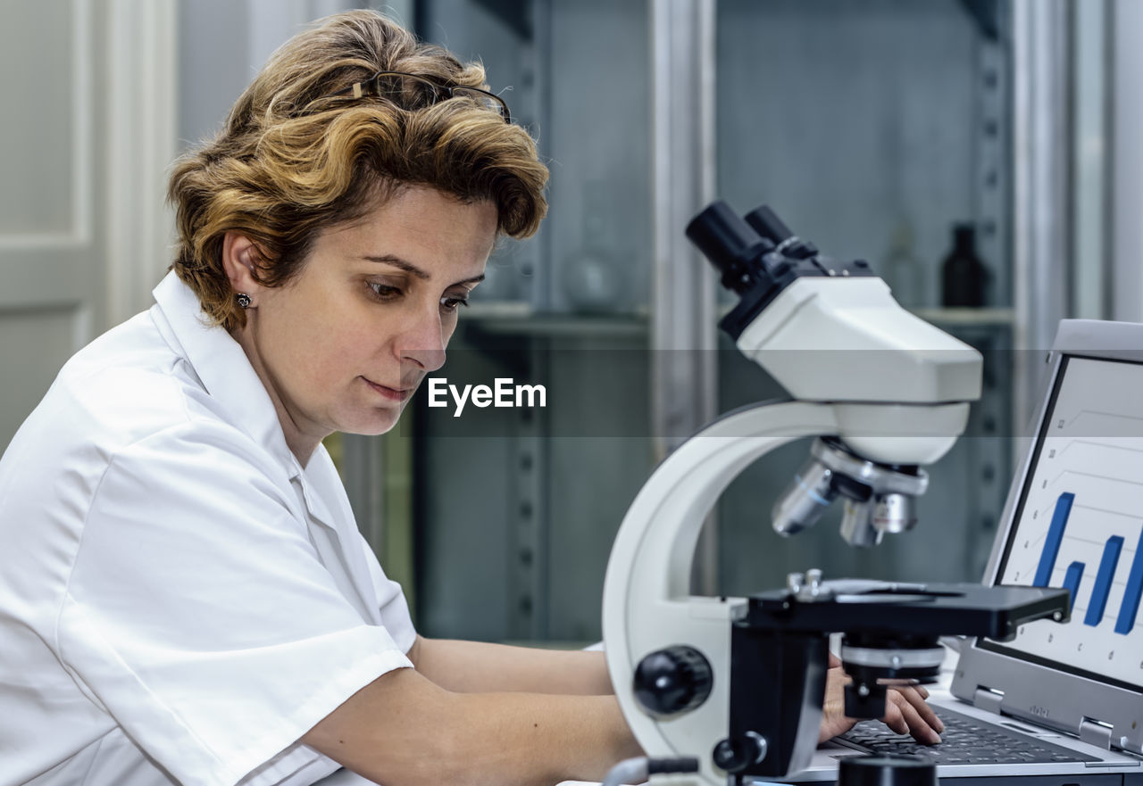 Close-up of scientist using laptop while sitting at laboratory