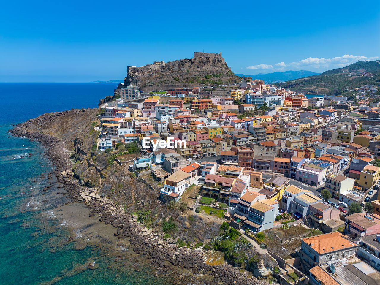 architecture, sea, building exterior, building, city, water, built structure, land, coast, town, sky, beach, nature, residential district, house, travel destinations, vacation, travel, cityscape, high angle view, blue, aerial photography, tourism, coastline, environment, landscape, scenics - nature, outdoors, no people, clear sky, horizon over water, community, roof, history, beauty in nature, trip, the past, mountain, bay, horizon, sunny, old, holiday, day, aerial view, transportation, summer, body of water, sunlight, village, urban skyline, street, religion, harbor