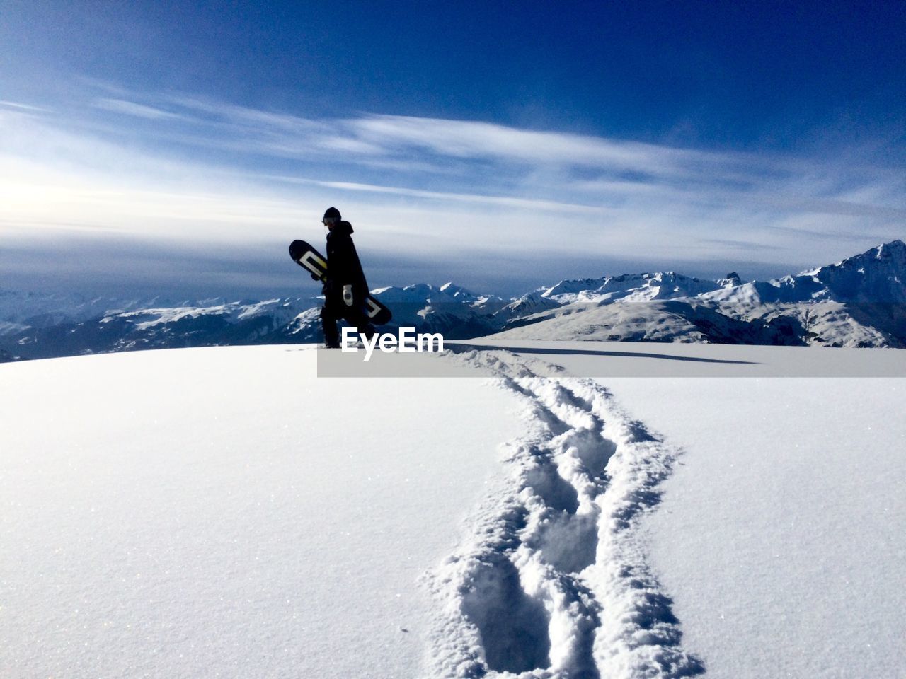 Man on snowboarding on snow covered mountain against sky