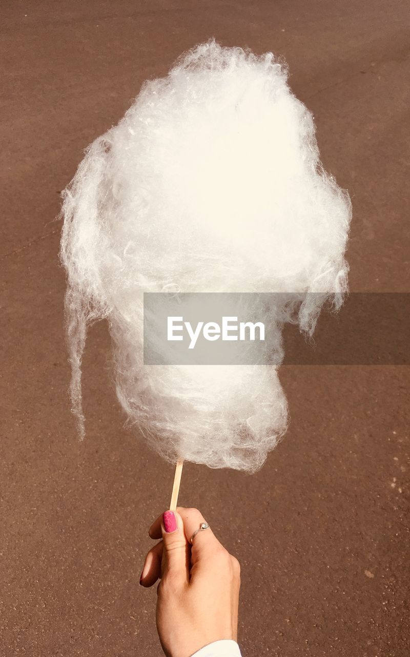 Cropped hand having cotton candy at beach