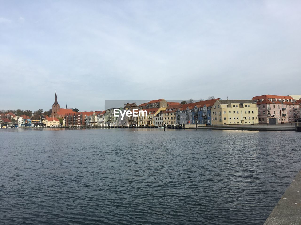 View of buildings at waterfront against cloudy sky