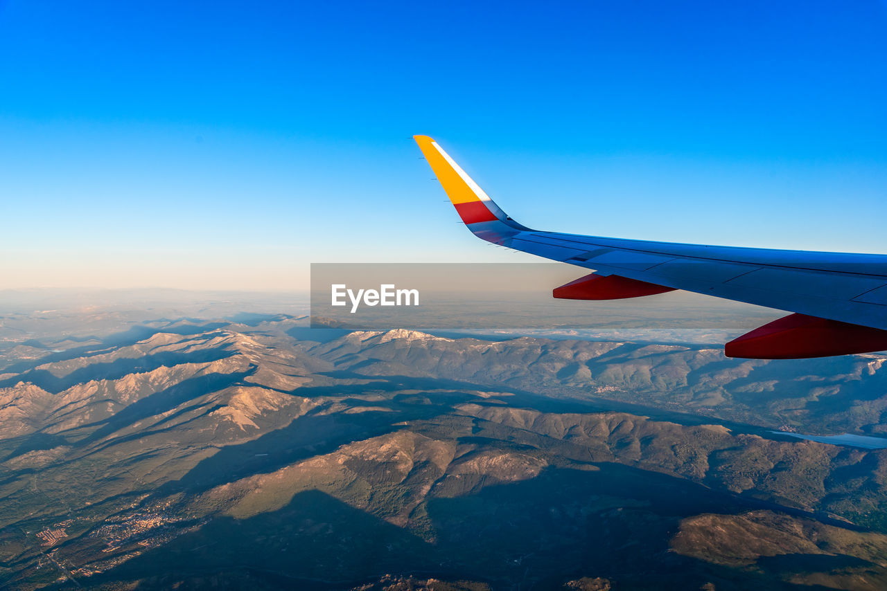 Wing of airplane flying over over mountain range. guadarrama, navacerrada. traveling concept