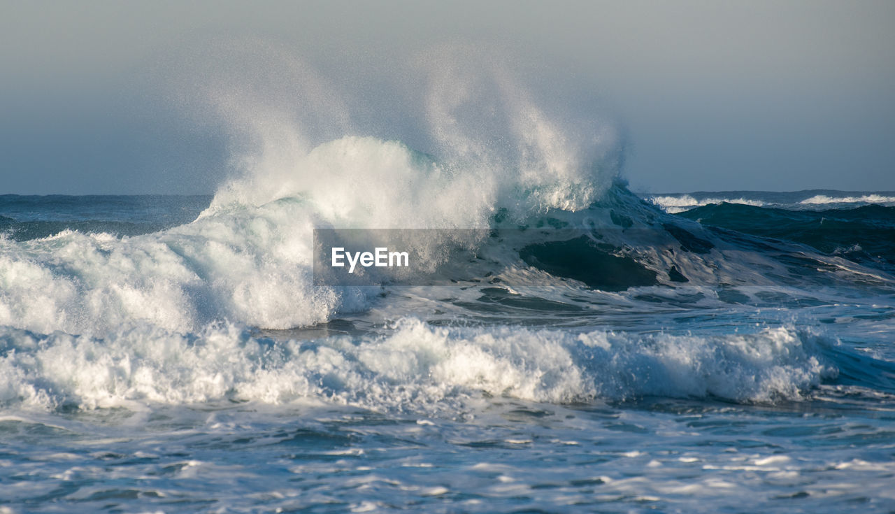 Waves splashing in sea against sky