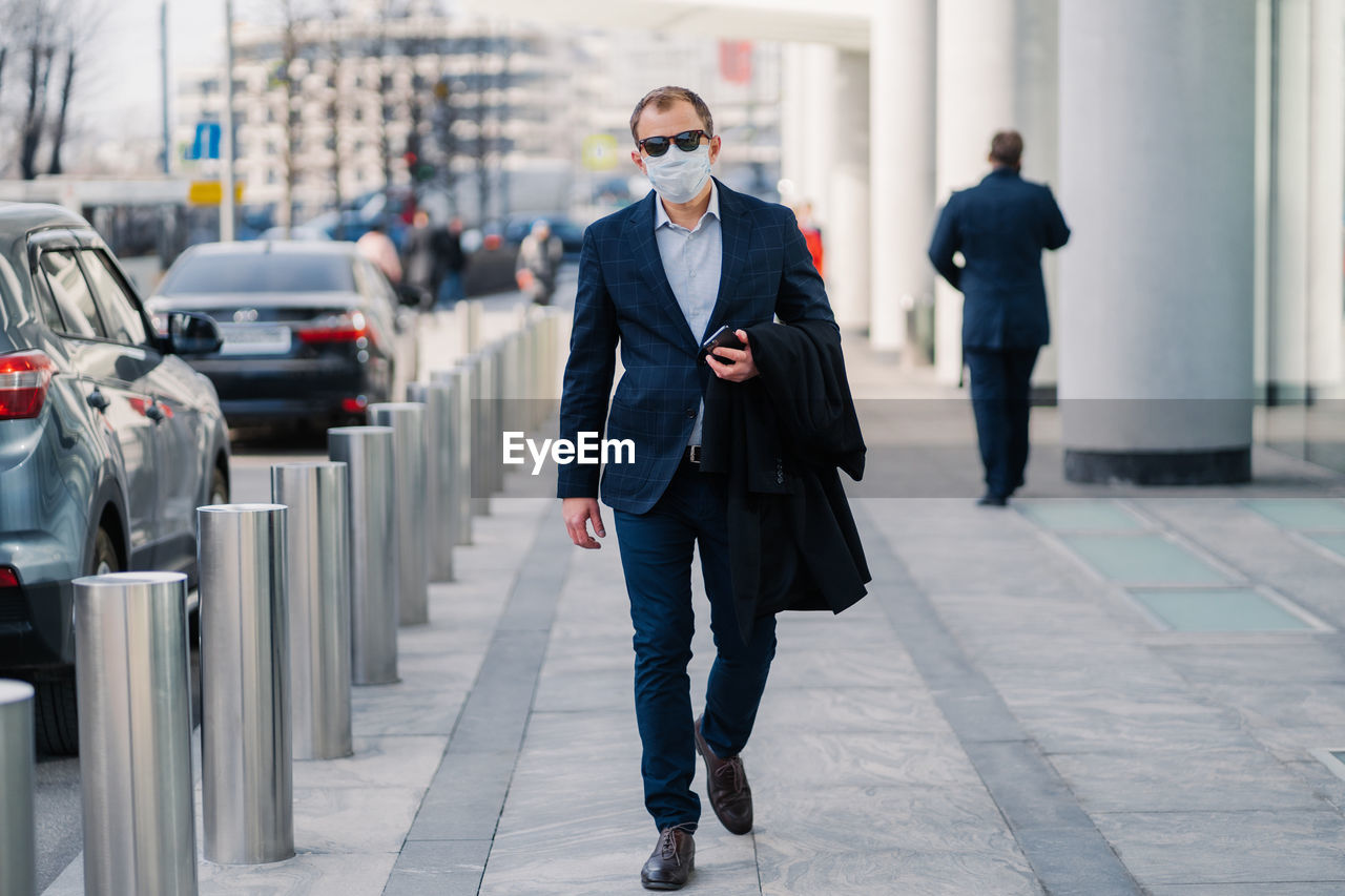 Businessman wearing mask walking in city