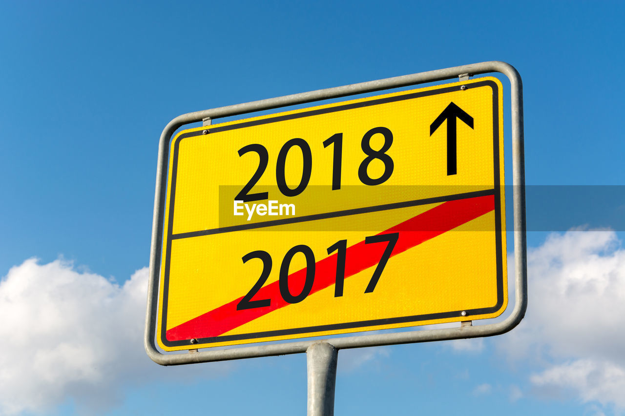 Low angle view of road sign against blue sky