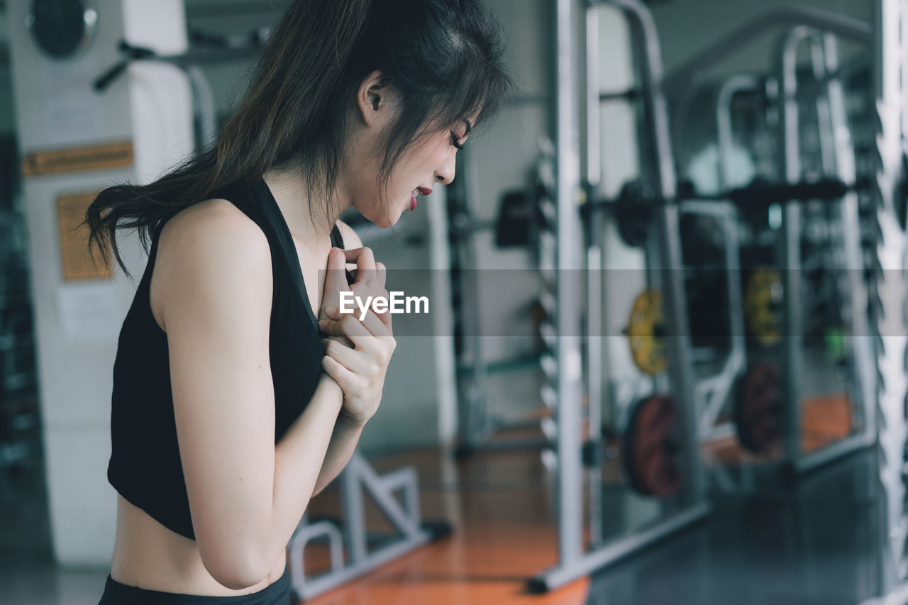 Young woman suffering from joint pain while exercising in gym