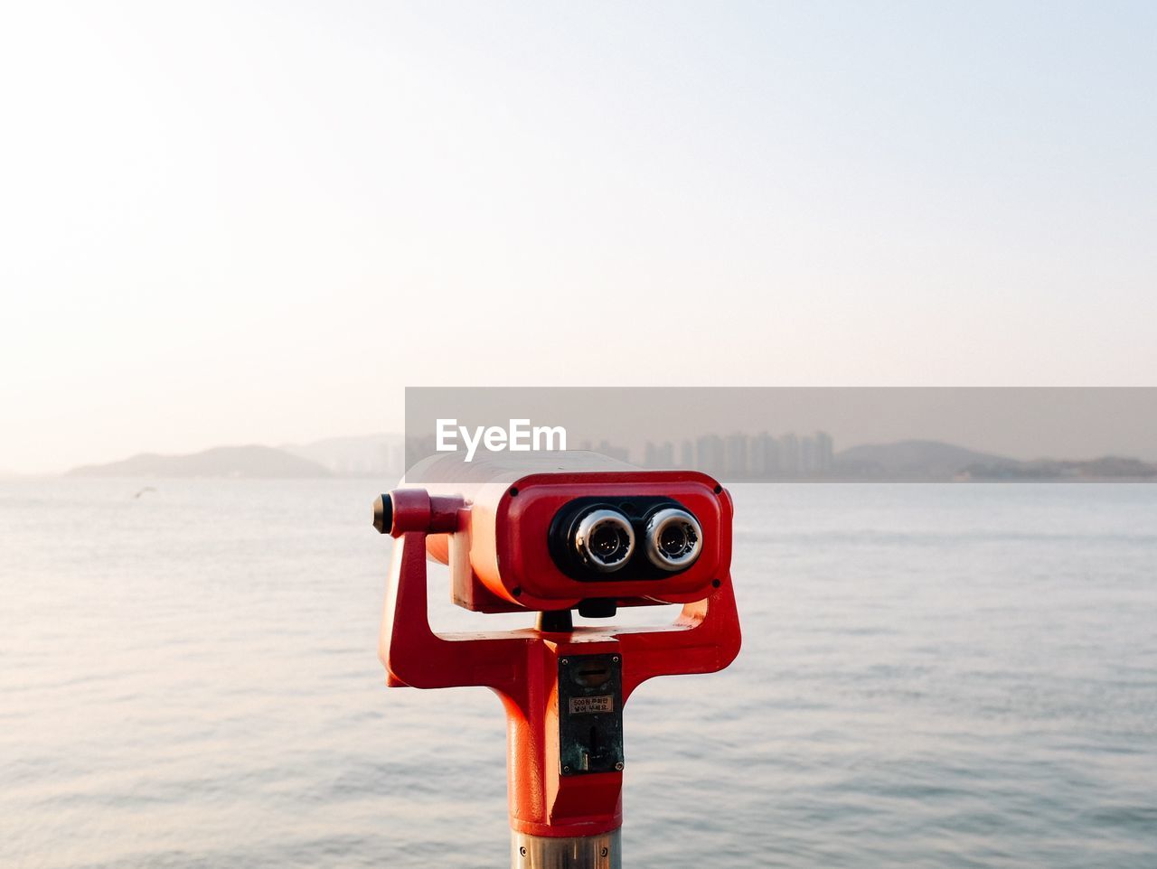 Close-up of coin operated binoculars facing sea