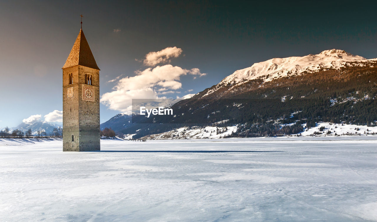 Bell tower in frozen lake reschen against sky