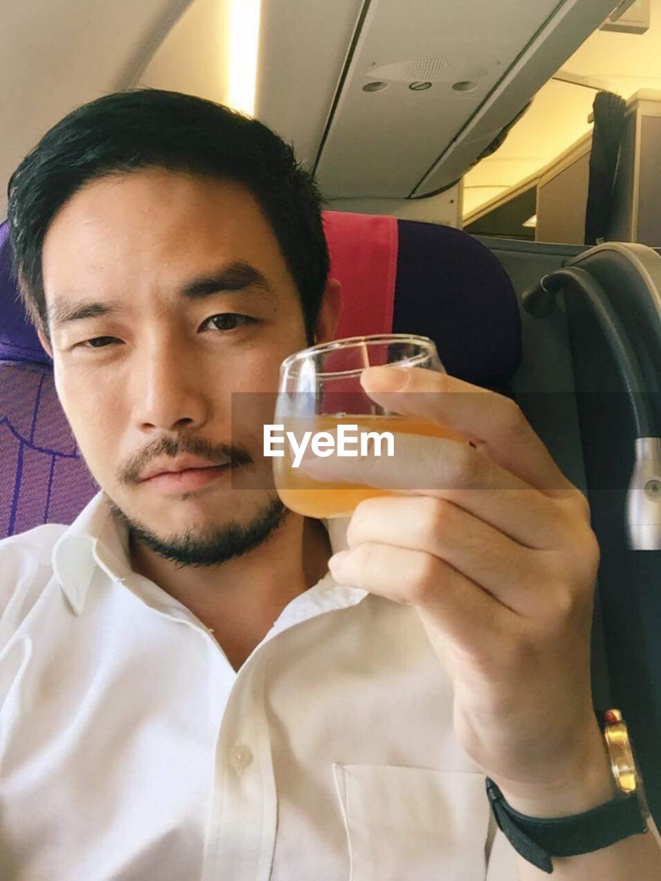 Close-up portrait of young man holding juice in glass