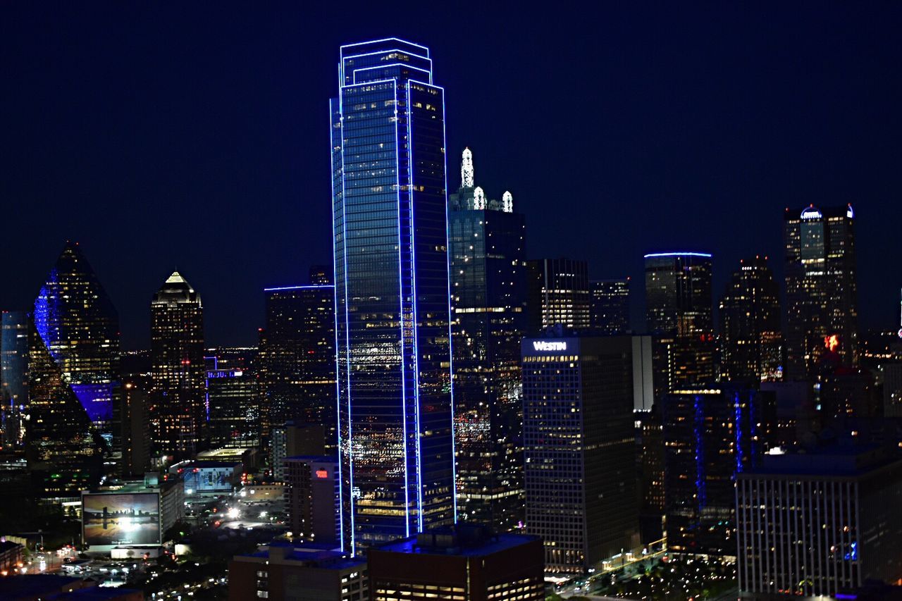 Illuminated cityscape against blue sky