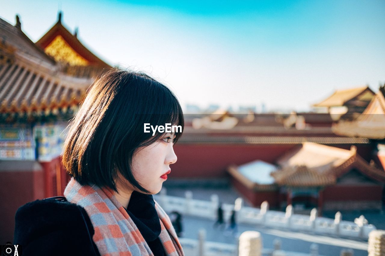 PORTRAIT OF YOUNG WOMAN LOOKING AT CAMERA AGAINST SKY