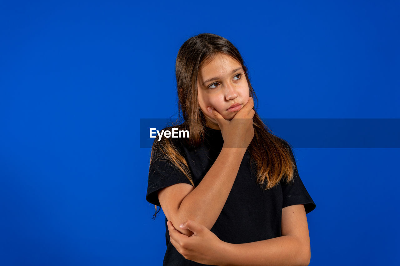 PORTRAIT OF A YOUNG WOMAN AGAINST BLUE BACKGROUND