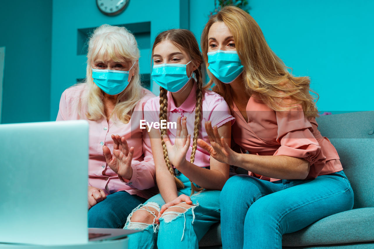 Happy family wearing mask talking on video call while sitting at home