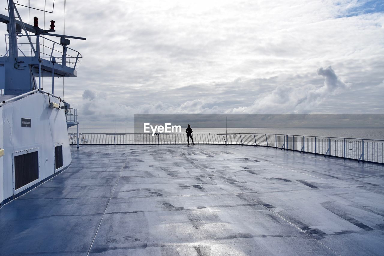 PERSON ON RAILING AGAINST SEA