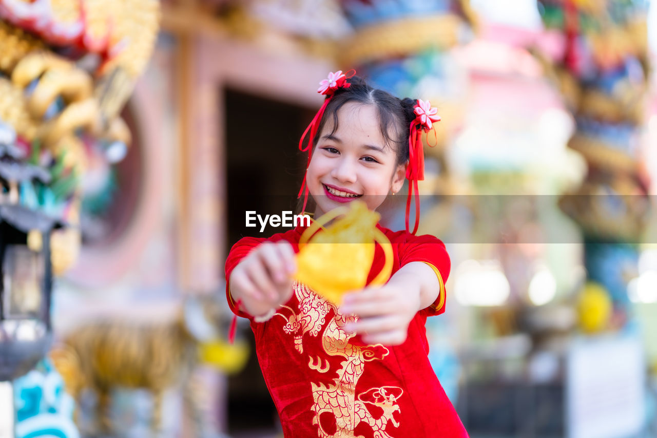 Portrait of smiling girl holding golden bag outdoors