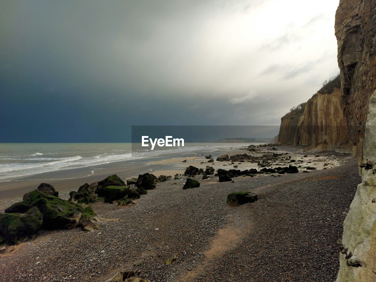 sea, land, beach, water, sky, rock, coast, ocean, shore, scenics - nature, cliff, nature, beauty in nature, cloud, wave, body of water, terrain, environment, coastline, horizon over water, sand, bay, horizon, tranquility, travel destinations, landscape, seascape, tranquil scene, no people, motion, outdoors, travel, dramatic sky, non-urban scene, water's edge, rock formation, tourism, wind wave, sunset, day, overcast, idyllic