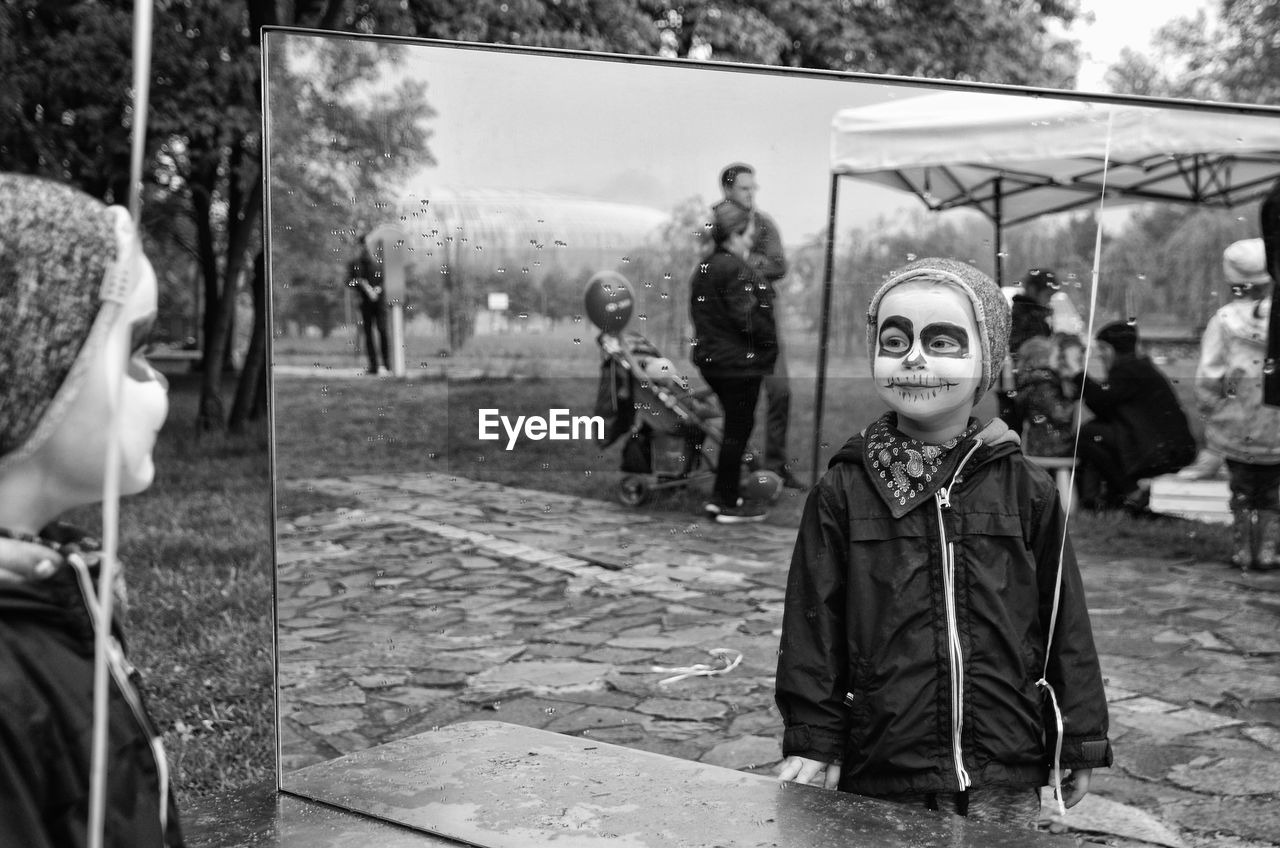 Smiling boy with face paint reflecting on mirror