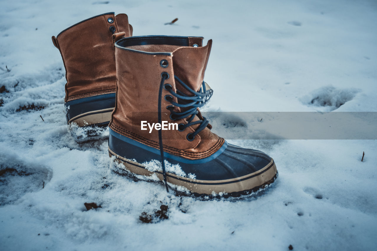 CLOSE-UP OF SNOW COVERED SHOES ON FIELD