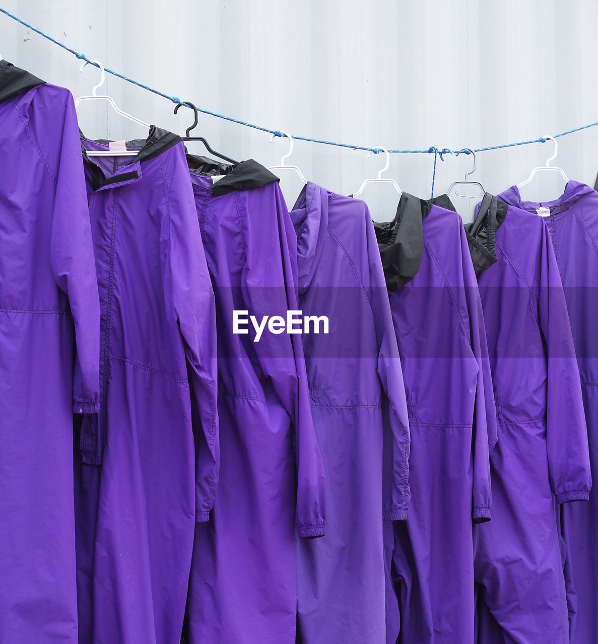 Close-up of purple uniforms hanging on rope