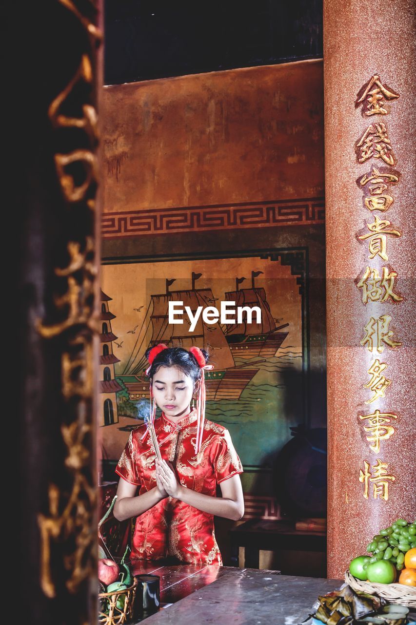 Girl praying while standing in temple