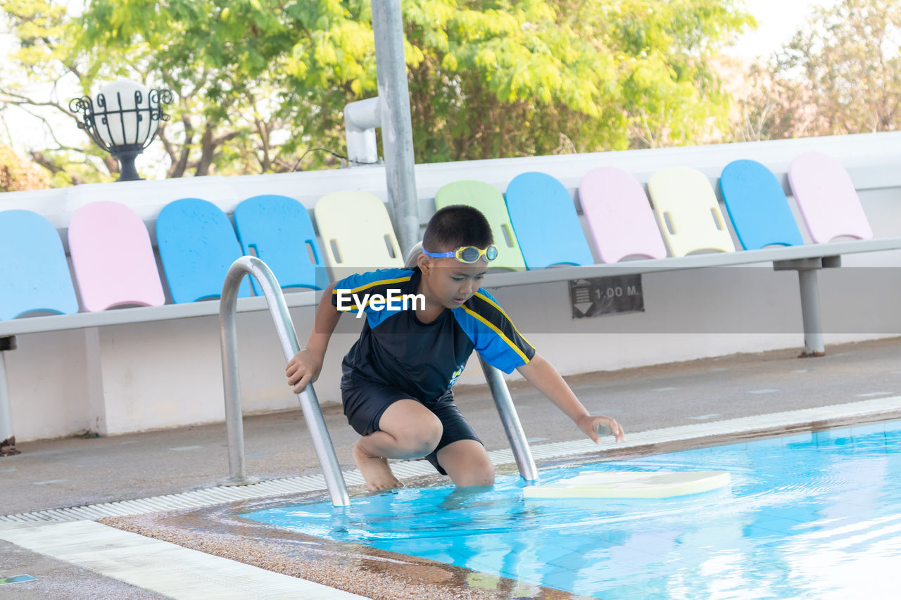 Full length of boy entering in swimming pool