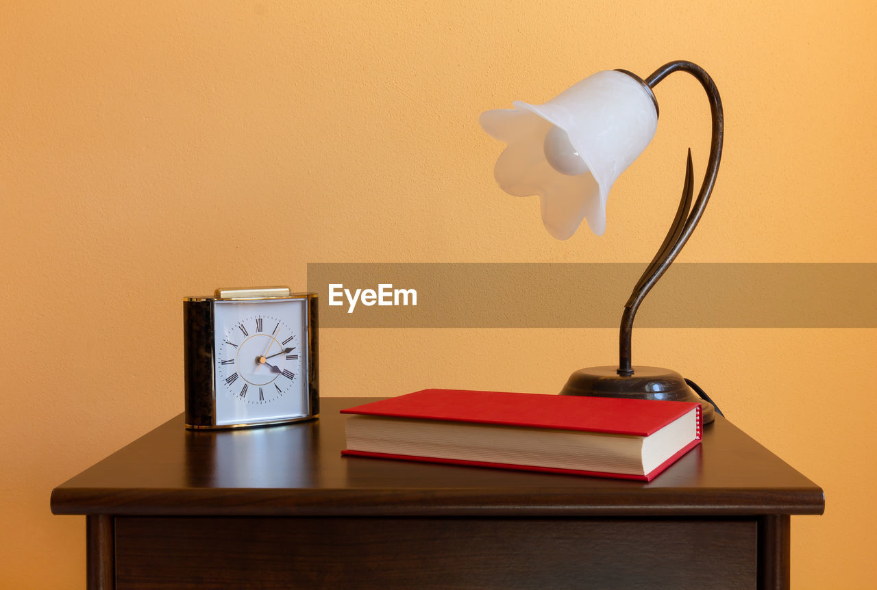 Close-up of lamp on table against wall at home