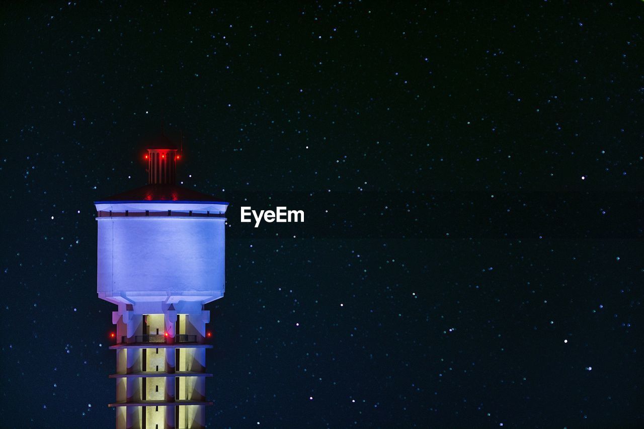 Illuminated water tank against star field at night