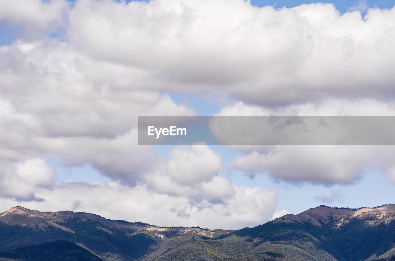 LOW ANGLE VIEW OF CLOUDS OVER MOUNTAINS