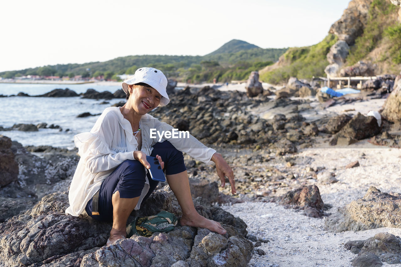 Portrait of a happy mature woman smiling outdoors. happy smiling mature woman on the rock 