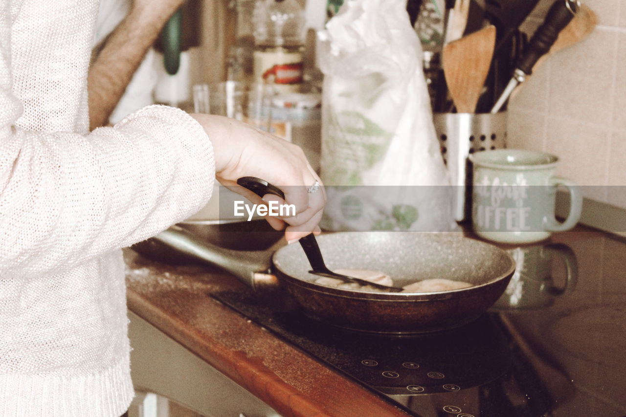 MIDSECTION OF PERSON PREPARING FOOD AT KITCHEN