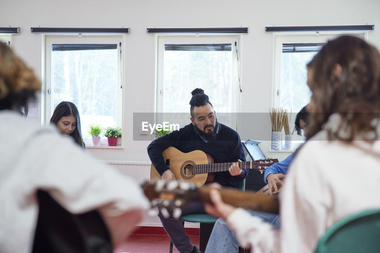 Teenagers attending guitar lesson