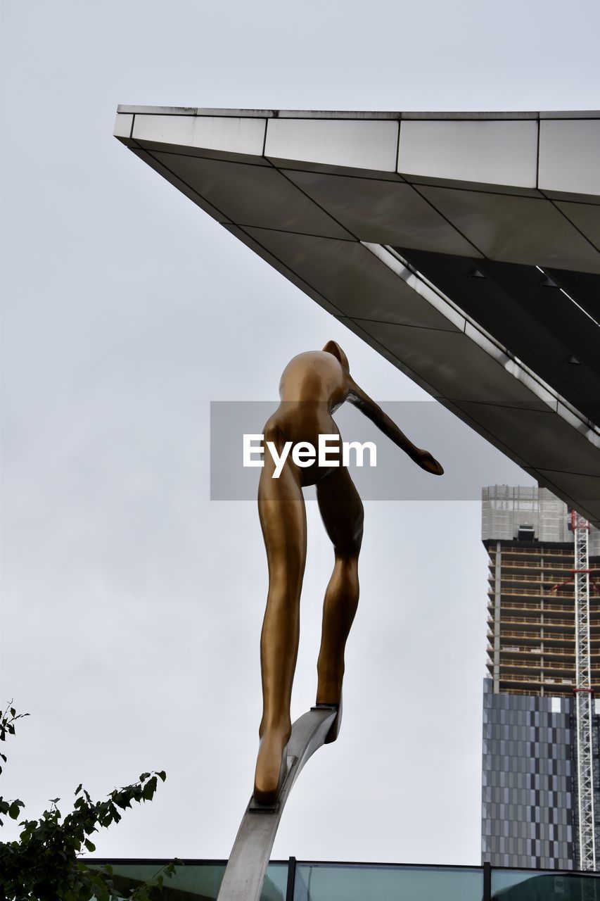 Low angle view of shirtless man sculpture against sky