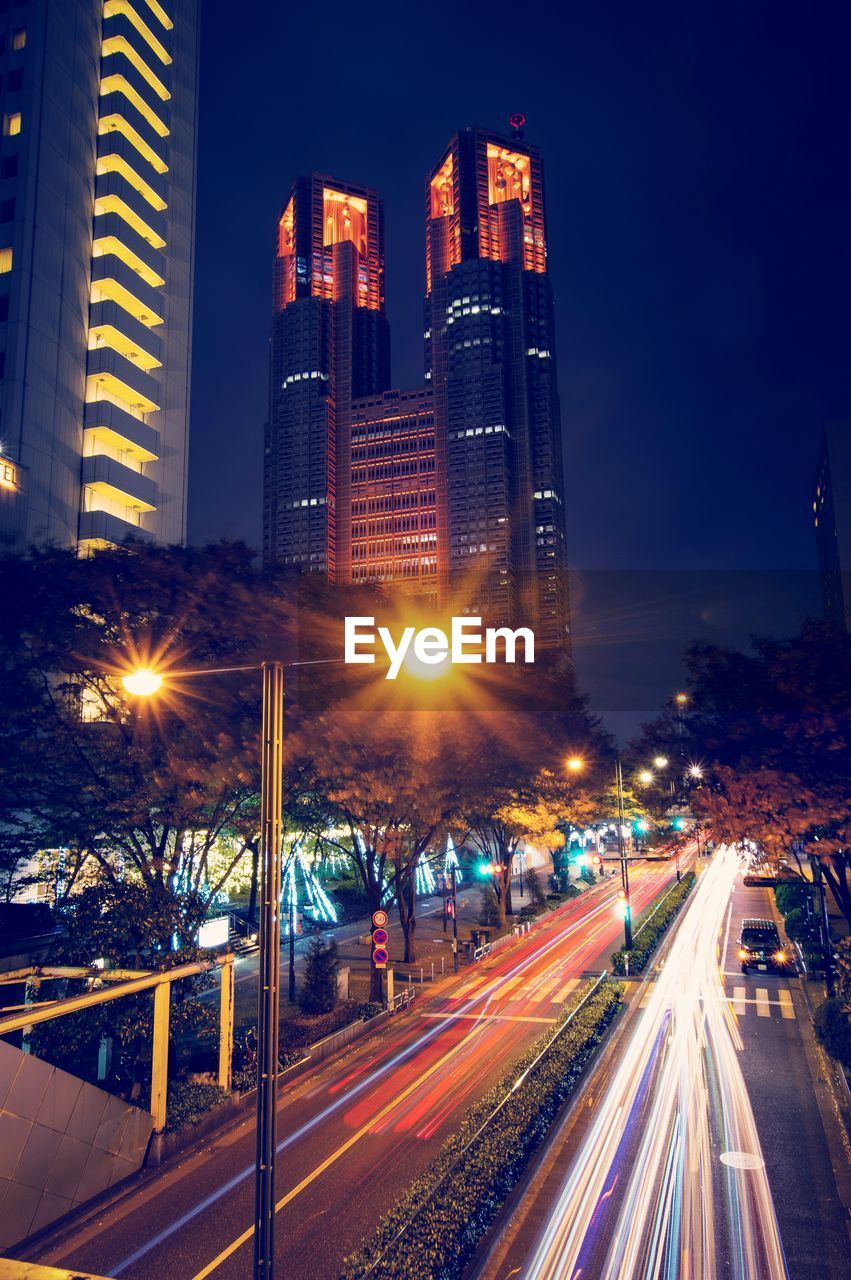 Light trails on road amidst buildings in city at night