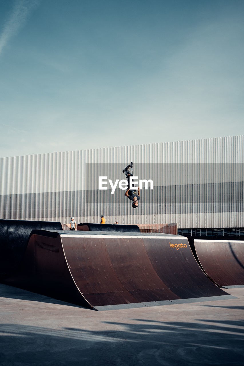 REAR VIEW OF MAN SKATEBOARDING ON SKATEBOARD