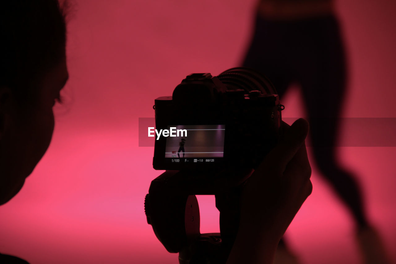 CLOSE-UP OF MAN PHOTOGRAPHING AGAINST BLACK AND CAMERA