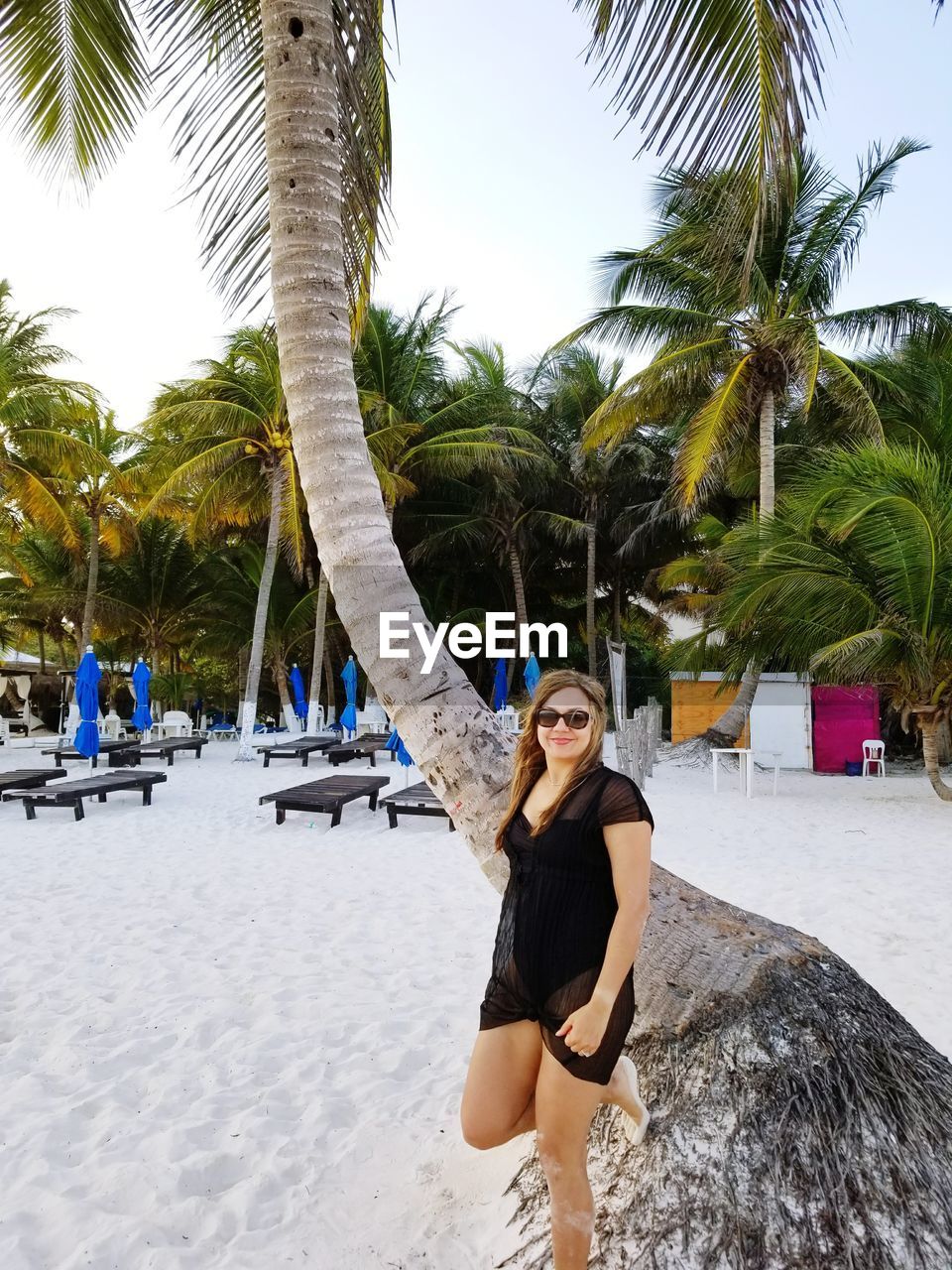 FULL LENGTH OF HAPPY YOUNG WOMAN STANDING AT BEACH