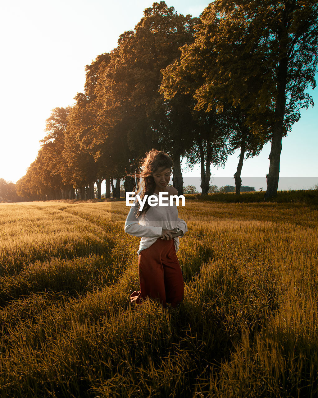 WOMAN WITH UMBRELLA ON FIELD AGAINST SKY