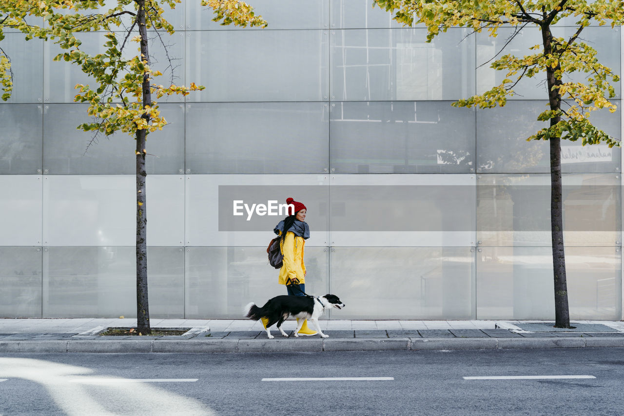 Woman walking with dog on footpath during autumn