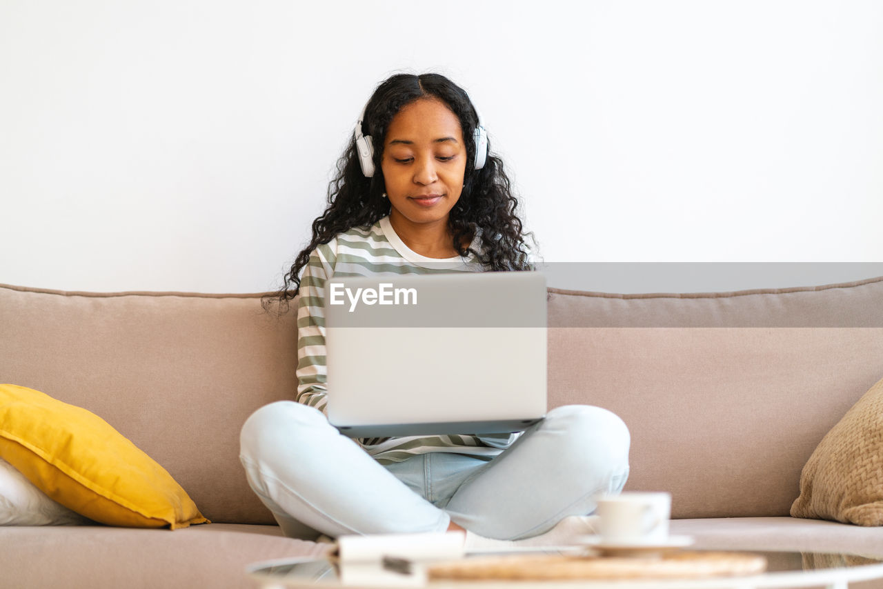 Attending online class from home. african-american student working on laptop, listening to lecture