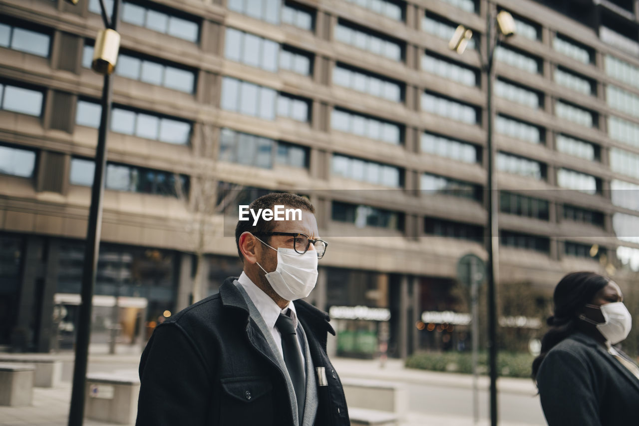 Mature business people in front of building during pandemic