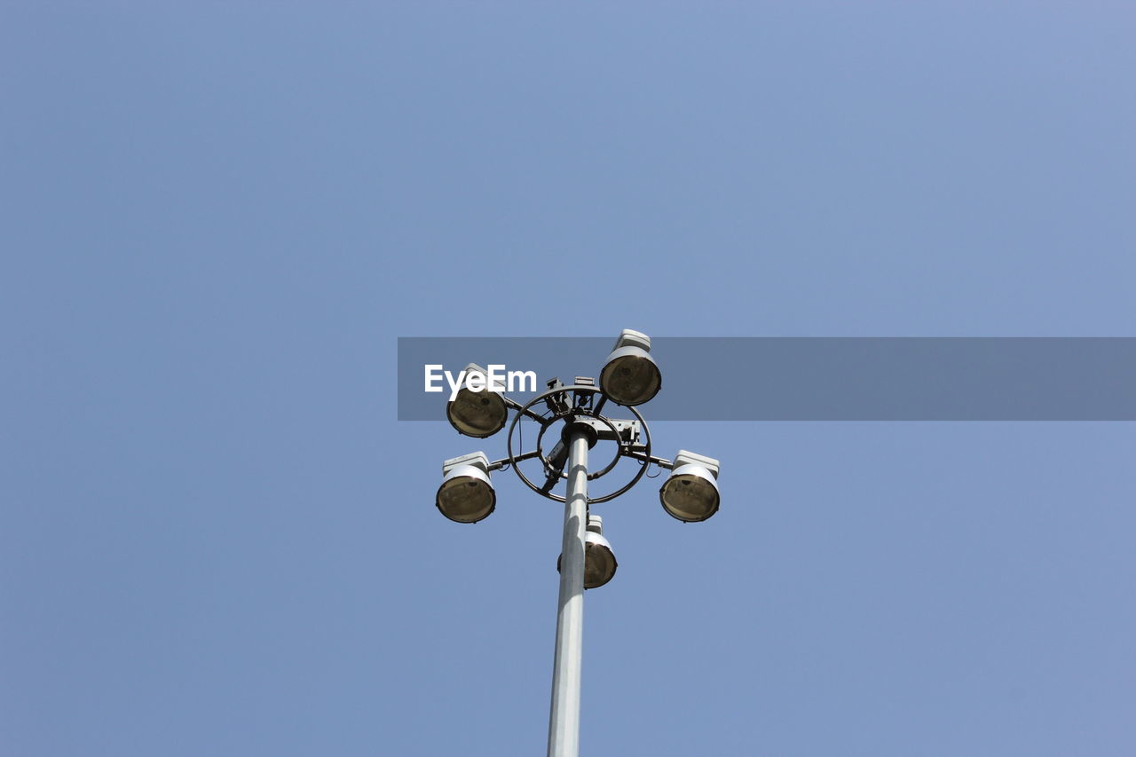 Low angle view of street lights against clear blue sky