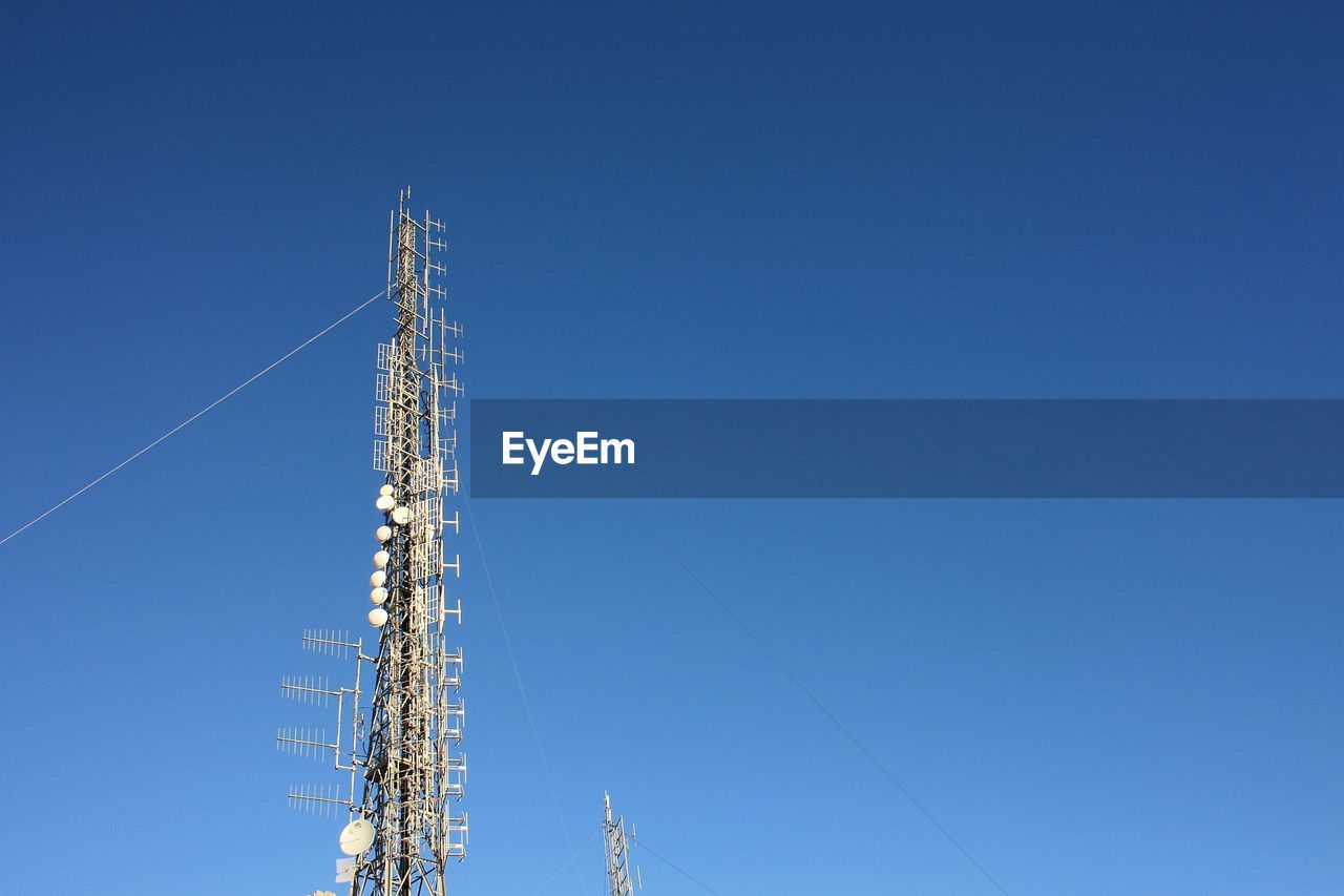 Low angle view of communications tower against blue sky