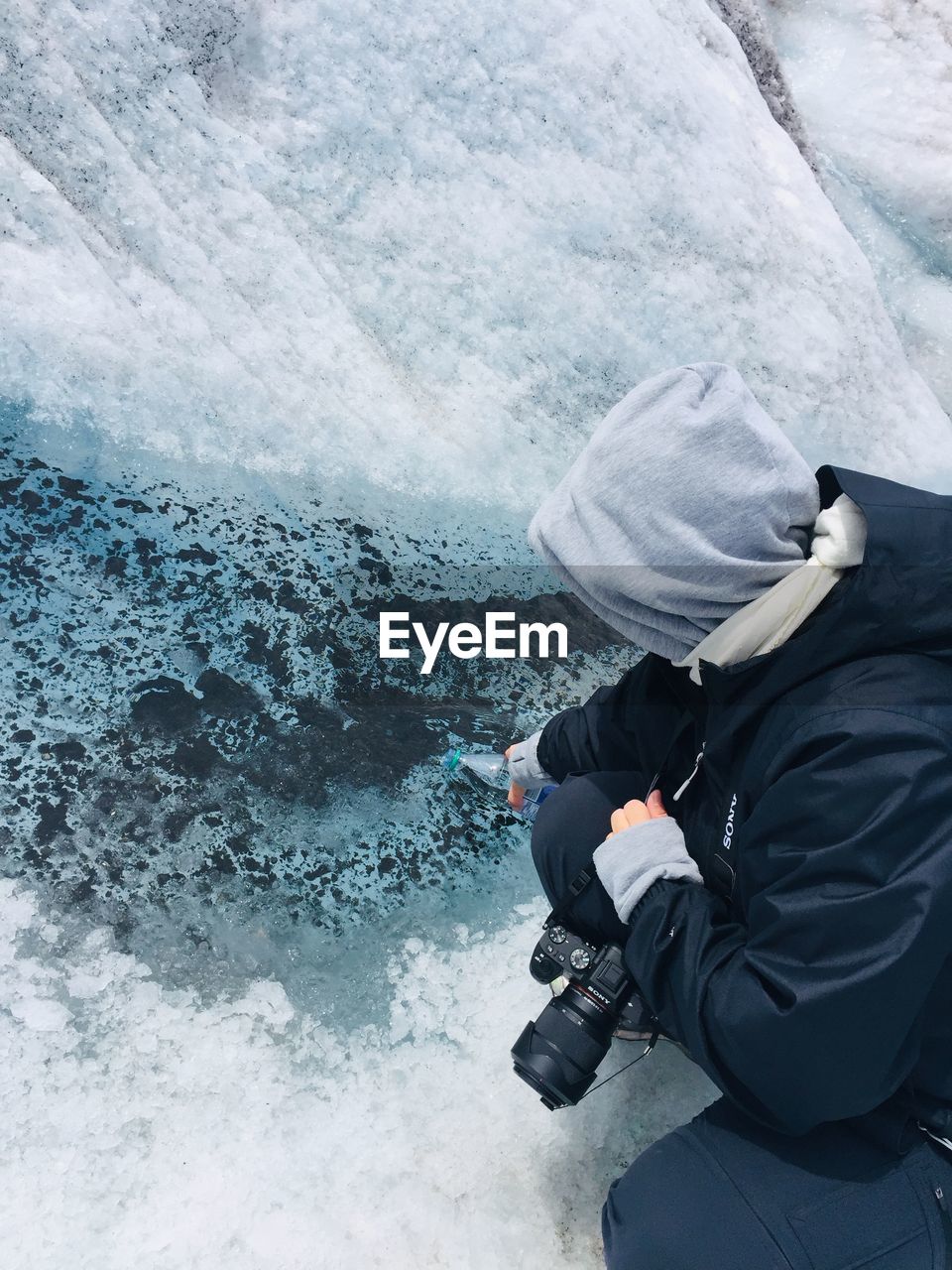 High angle view of person filling water bottle from river