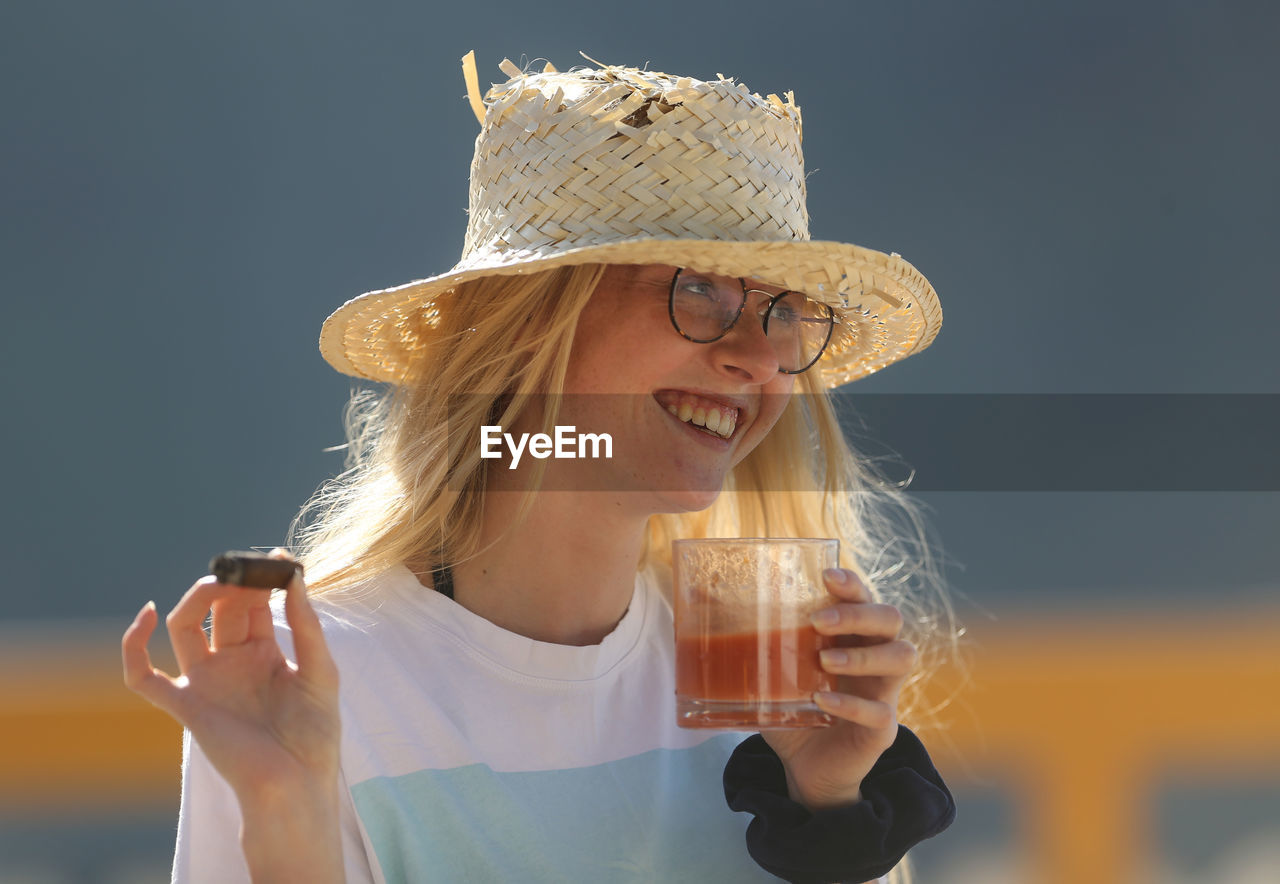 MIDSECTION OF A YOUNG WOMAN DRINKING DRINK