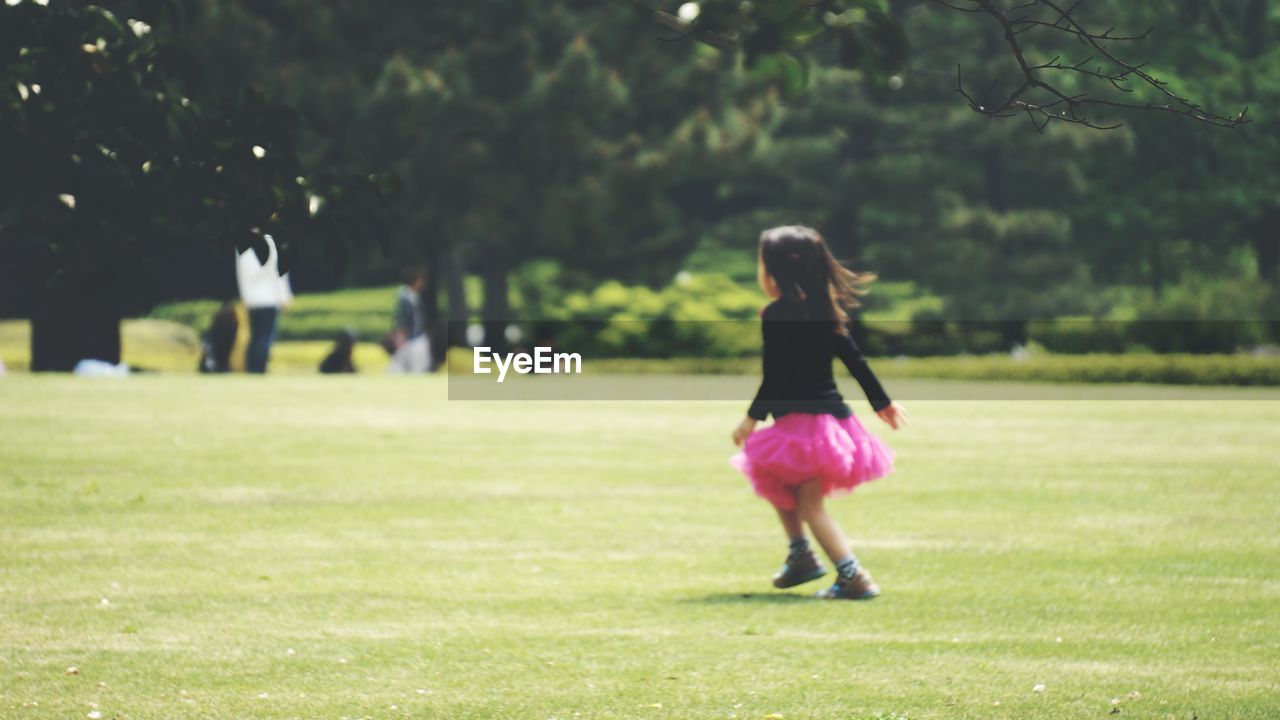 FULL LENGTH OF WOMAN WALKING ON GRASSY FIELD