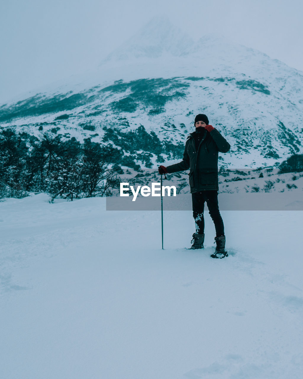 Full length portrait of man standing on snow against mountain and sky