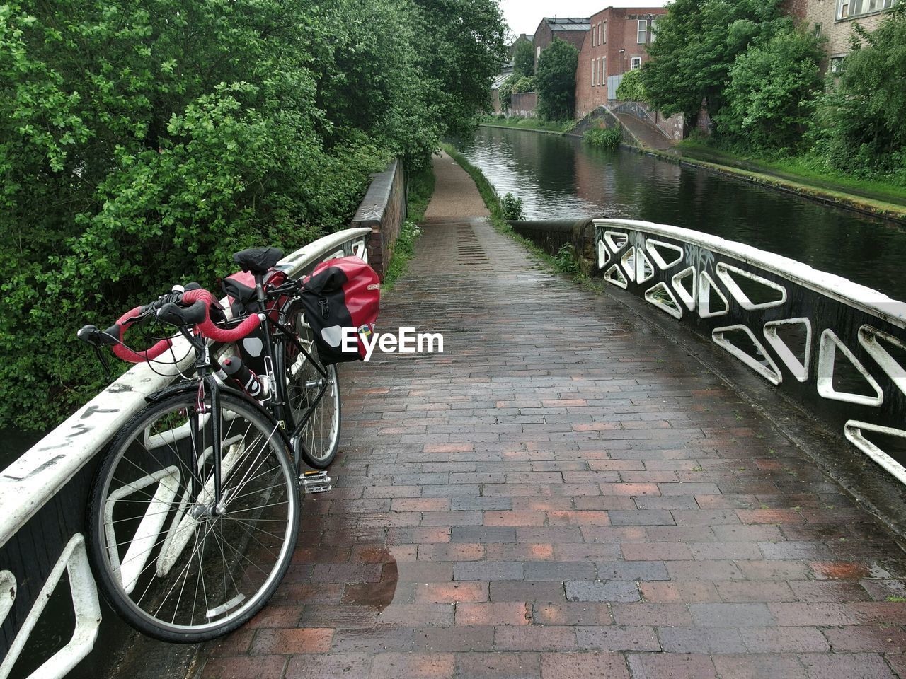 A bicycle stands on a bridge parallel to a canal