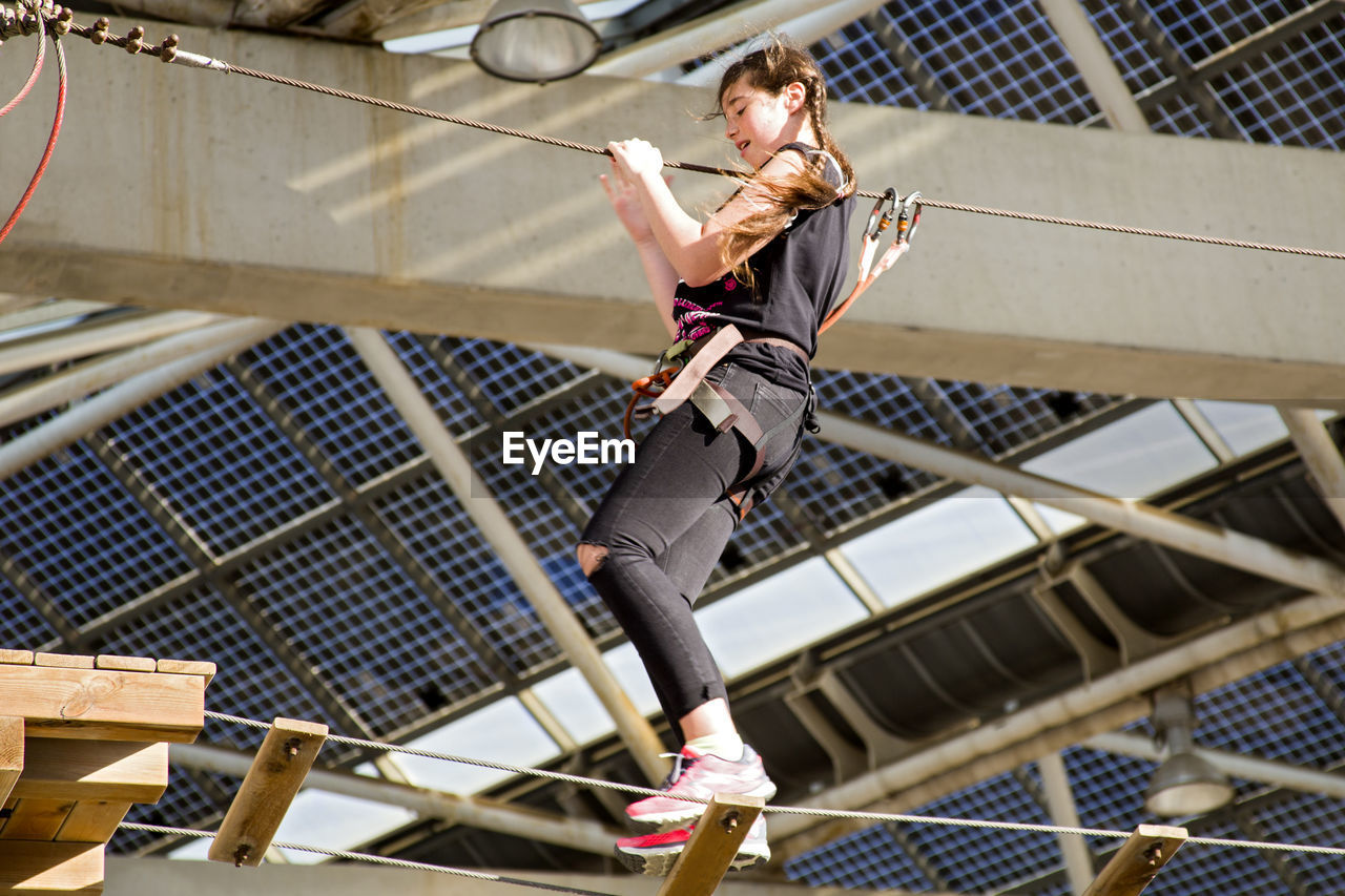 Low angle view of teenage girl walking on rope