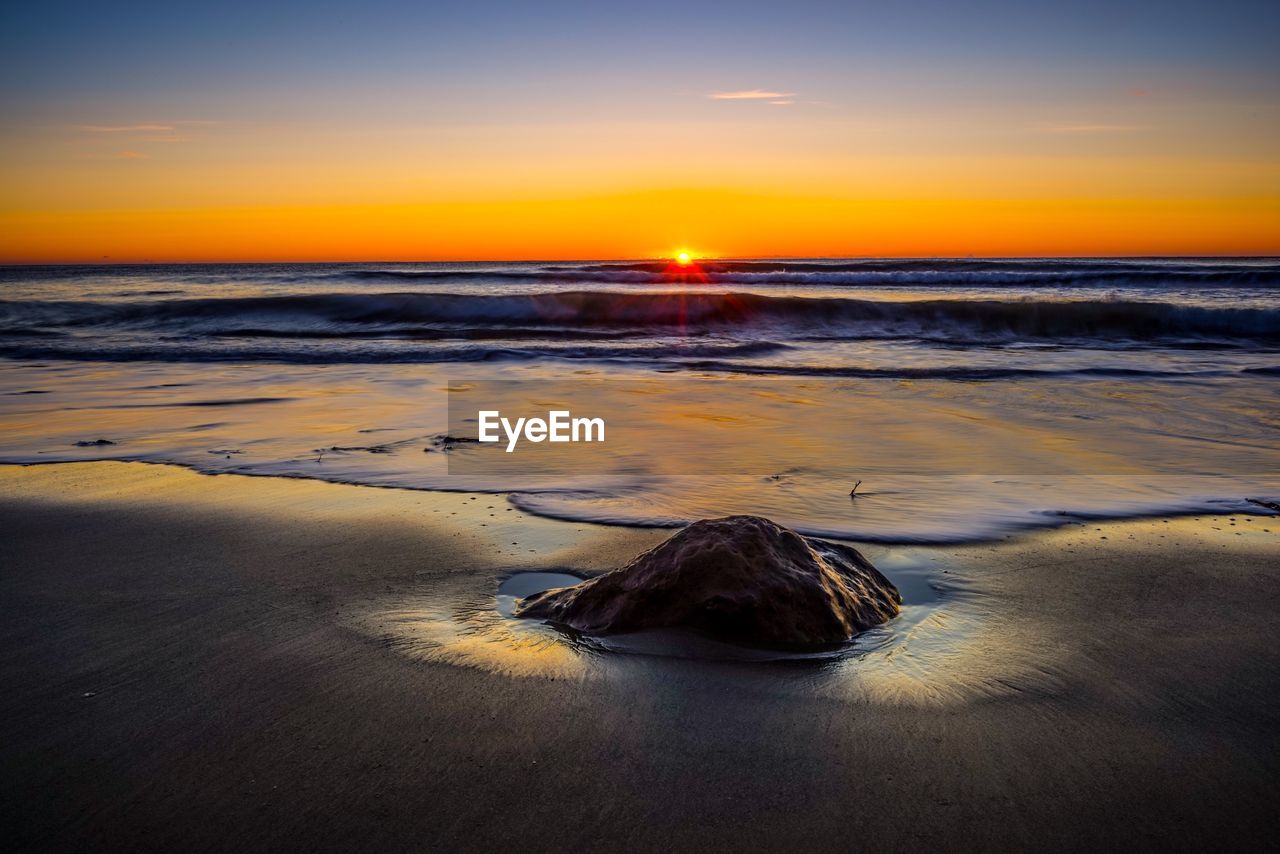 SCENIC VIEW OF BEACH AGAINST SKY AT SUNSET